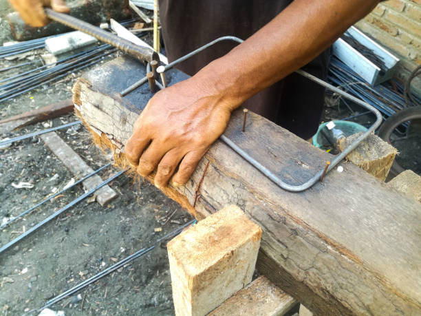workers are working on bending steel rods into stirrups at a construction site. hand in frame