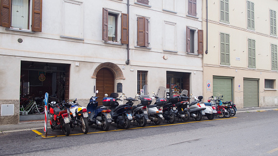 Cremona, Italy - May 11 2023 street row of parked old scooter and repair shop mechanich garage
