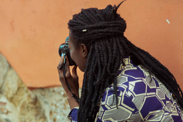 Portrait of an woman with dreadlocks smiling while making a photograph with reflex camera.