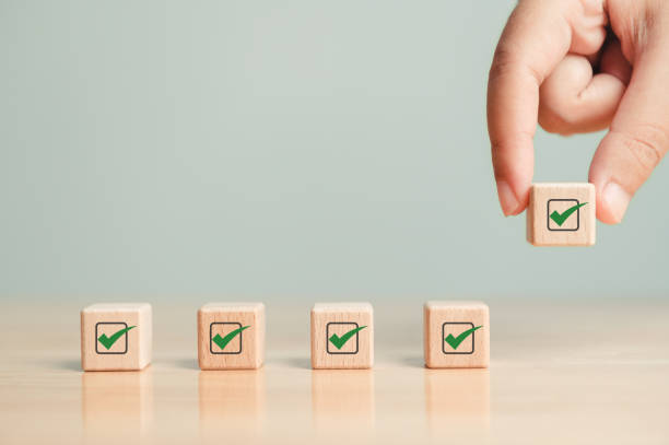 Wooden blocks checklist and green check mark icon with hand on table background. Business task sign appointment schedule concept. Businessman placing correct evaluation satisfaction checkbox symbol lista de verificación de bloques de madera e icono de marca de verificación verde con la mano sobre el fondo de la mesa. concepto de horario de citas de firma de tareas comerciales. hombre de negocios colocando el símbolo de la casilla de verificación