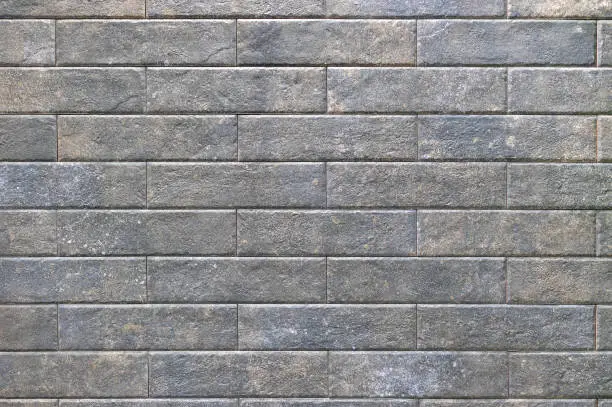 Photo of The texture of stone tiles laid in a row on the wall in even rectangles.