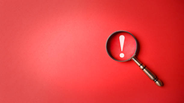 Magnifier magnifying exclamation mark on red background. Alert and precaution concept. Caution and risk management security signal announcement hazard and dangerous notice symbol