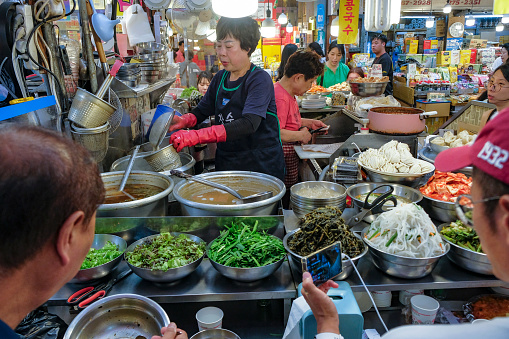 Seoul, South Korea - June 23, 2023: A woman preparing food at the Gwangjang Market in Seoul, South Korea.