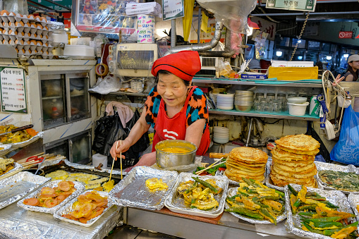 Seoul, South Korea - June 23, 2023: A woman preparing food at the Gwangjang Market in Seoul, South Korea.