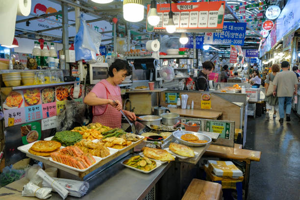Seoul, South Korea - June 23, 2023: A woman preparing food at the Gwangjang Market in Seoul, South Korea.
