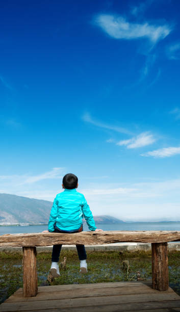 istock Little boy sitting beside the lake 1502101728