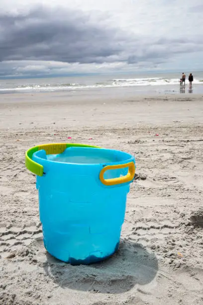 abandoned blue bucket on the sand at the beach, not being played with, copy space