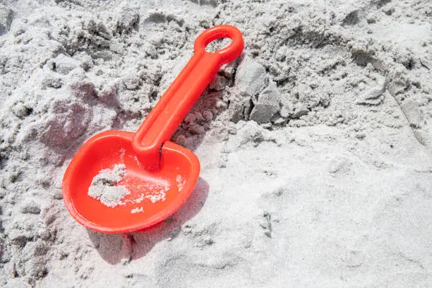 broken orange shovel on the sand at the beach, not being played with, copy space