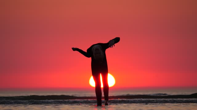 Cheerful girl stand and look to sunset, then bend back and wave hand to camera