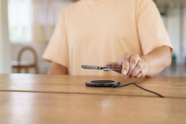 istock Charging mobile phone battery with wireless charging device in the table. Smartphone charging on a charging pad. Mobile phone near wireless charger Modern lifestyle technology concept. 1502123333