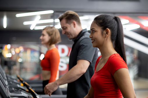 Group people workout with walking and exercise on machine treadmill together in fitness gym sport club, man and woman cardio with training jogging, diversity and ethnicity, healthcare and motivation.