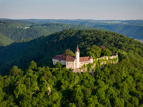 Owen, Germany - June 11, 2023: South-West  German Swabian Alb in Summer. Aerial Drone view over green summer Swabian Alb Hill with Burg Teck - Teck Castle on top a green hill illuminated from warm sunset light. DJI Mavic 3 Pro Aerial Photo. Teck Castle, Owen, Swabian Alb, Baden Württemberg, Southern Germany, Germany, Europe.