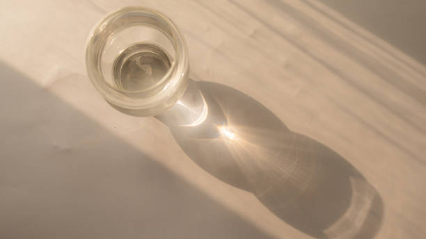 istock Glass cup on table with reflection of sun rays 1502131301