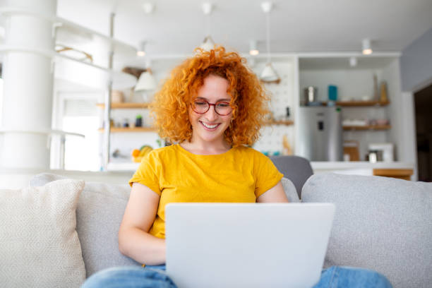 istock Woman sitting with computer on sofa, studying at home, e-learning and remote freelance job concept 1502135516