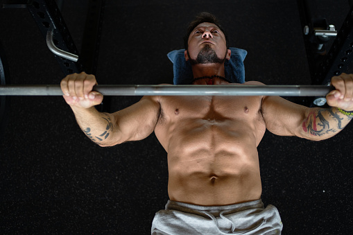 Top view of an athletic and strong man doing press bench exercise in a gym