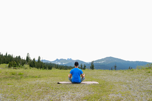 Men stand with yoga mat in mountains landscape. Outdoor yoga in mountains. Copyspace