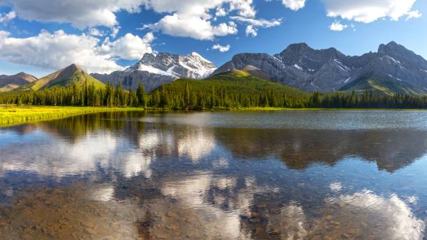 Beautiful Panoramic Landscape, Kananaskis Country Wilderness, Alberta Canadian Rockies Clouds and Distant Rocky Mountain Peaks Reflected in Calm Blue Lake Water kananaskis country stock pictures, royalty-free photos & images