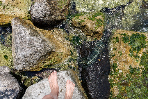 Two bare feet on sea rock in sunlight