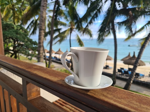 Cup of tropical coffee on beach balcony. Paradise island and morning in Asia