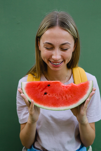 Cute caucasian woman with braces eats a watermelon