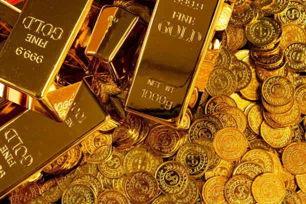 Gold bars are placed on a pile of gold coins