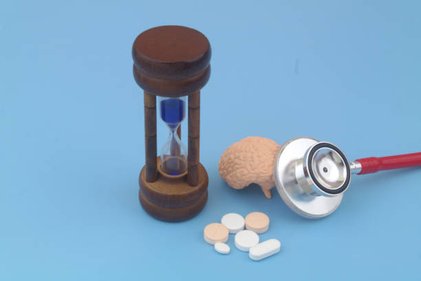 Human brain with red stethoscope, medical drugs and hourglass on blue. Human brain with red stethoscope, medical drugs and hourglass on blue background. Understanding Dosage and Timing stock pictures, royalty-free photos & images