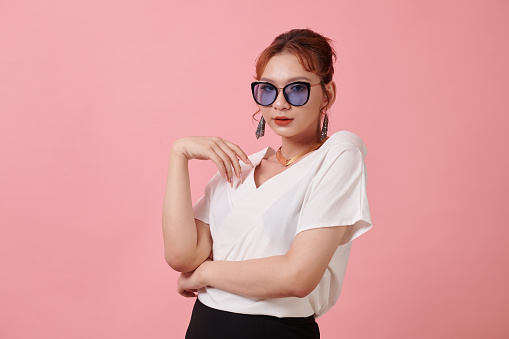 Studio portrait of fashionable transgender woman in white blouse and sunglasses