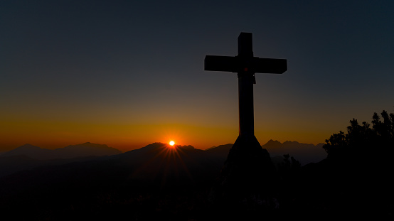 Mountain top with cross in the setting sun