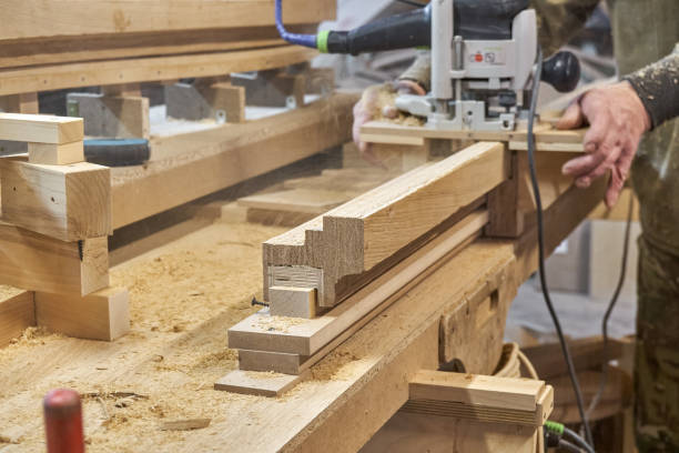 Carpenter milling wooden handrail with manual milling machine Carpenter milling wooden handrail with router manual milling machine in workshop close up. Handyman processes timber piece with electric instrument rough hands man stock pictures, royalty-free photos & images