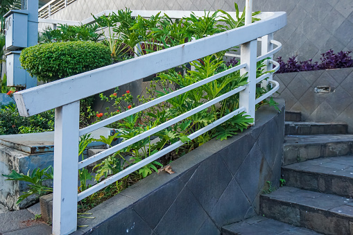 outdoor white iron fence between stairs and garden in shopping mall