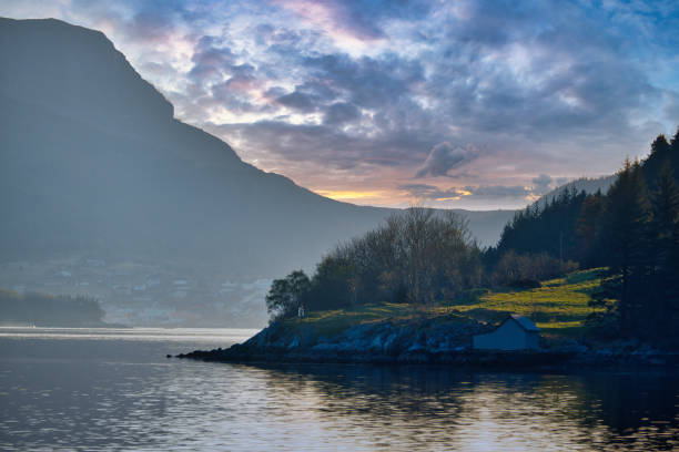 istock Sunset on the fjord with mountains in Norway. Diffuse light, sun rays on a meadow 1502209636