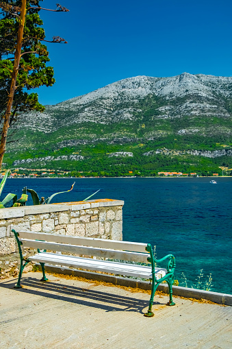 An empty bench with view of Adriatic Sea and majestic mountain range facing Korcula Island, Croatia, Europe.