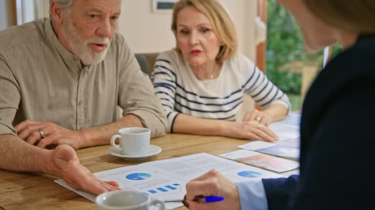 Senior couple talking to a female financial advisor at the dining table