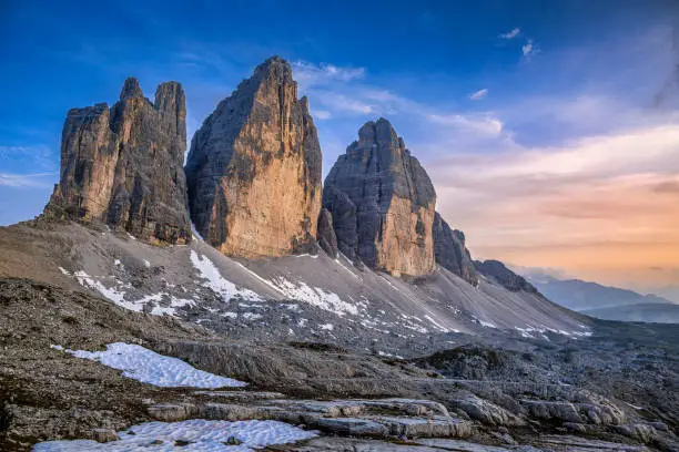The cliffs of the Tre Cime di Lavaredo peaks shine in golden colors during a summer sunset in the Italian Dolomites.