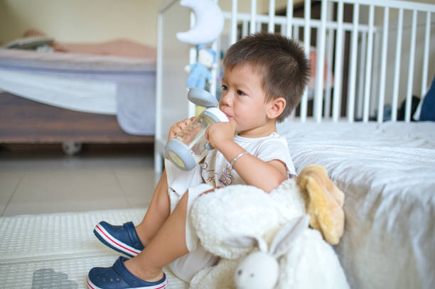 istock Toddler sitting on the playing mat and drinking milk from a straw bottle 1502220565