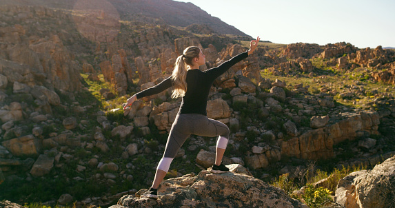 Woman, yoga and fitness on mountain rock in nature for spiritual wellness, mind and body in the outdoors. Fit female person, yogi or hiker in natural pose for exercise, training or healthy workout