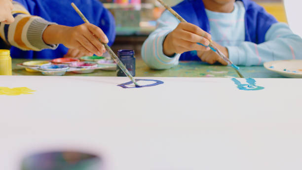 istock Closeup, hands and students painting, education or artwork with fun, creativity or watercolor. Zoom, children or kids with fantasy, youth or brushes to relax, inspiration or creative with imagination 1502226773