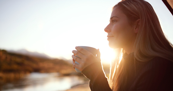 Woman, sunshine and camp coffee by a river in morning in summer by lake. Mockup, young female person and tea at sunrise on holiday, travel and vacation with hot drink and freedom from camping outdoor