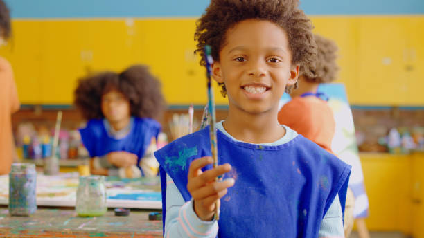 istock Happy boy, paintbrush and portrait in classroom with learning, development and group of school kids for art. Young male child, smile and excited face for education, creativity and painting at academy 1502233461