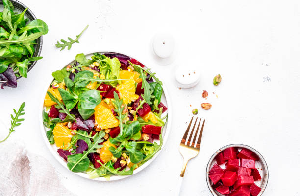 istock Beetroot and orange salad with arugula, lamb lettuce, mini chard and pistachios, white table, copy space.. Fresh useful dish for healthy eating 1502242550