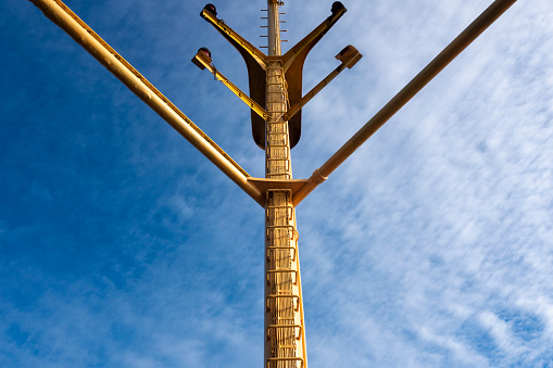 Ship antennas. Blue sky and yellow painted mast.