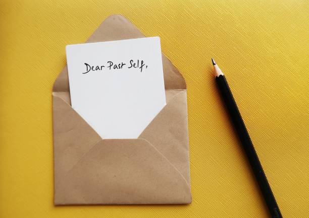 istock On yellow background, white card in craft envelope with handwriting DEAR PAST SELF, concept of self reflection - writing letter to the person you were, advice to give to tell about what happened then and now 1502252423