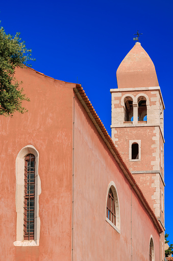 Beautiful low angle view on terracotta color church with bell tower against clear blue sky, Rab town on Rab island in Croatia