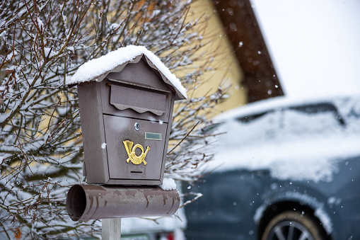 Old retro style metal mailbox covered in snow by parked car,winter time concept