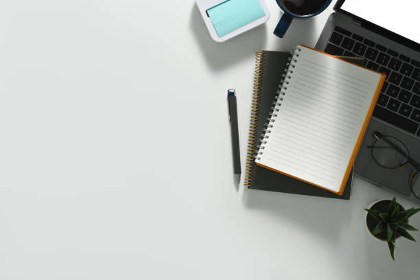 istock White office desk with blank notepad, laptop computer, and cup of coffee. Top view with copy space. 1502264351