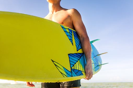 portrait of a surfer holding his board on the beach