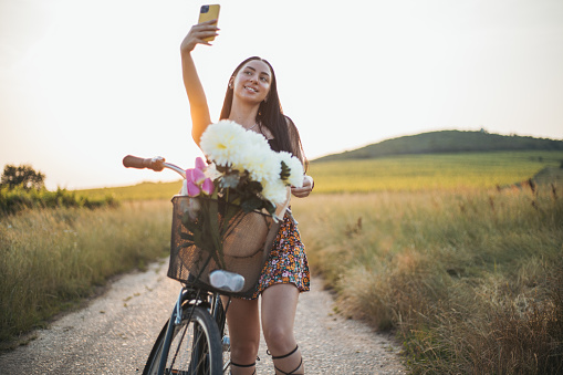 woman taking a break from riding bike to use smartphone for selfie
