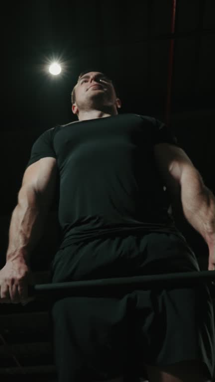 Vertical Screen: Muscular man bodybuilder lifting barbell in gym