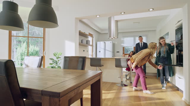 Male real estate agent showing the kitchen in a modern home to a female couple