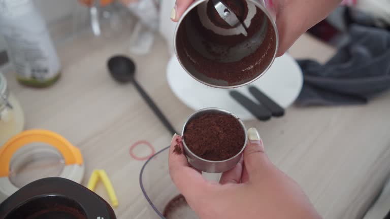 a person pouring ground coffee into a moka pot.